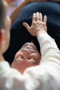 Osteopathische Schmerztherapie – Therapeut legt sanft die Hand auf die Brust eines liegenden Patienten zur Linderung von Schmerzen